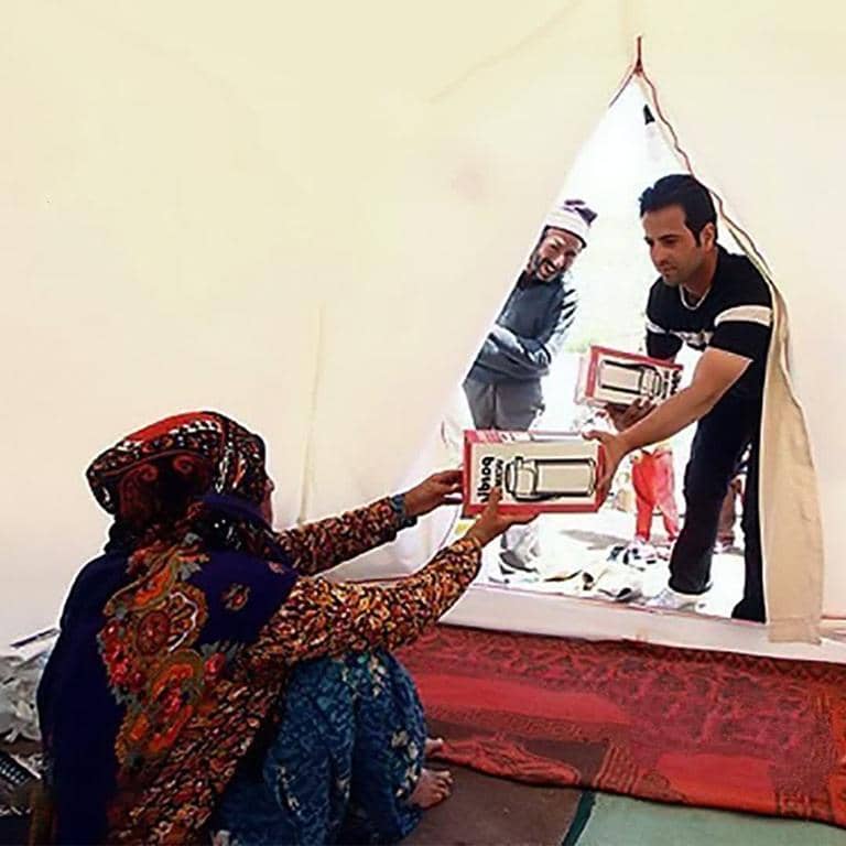 A woman receives a box of items from a man, symbolizing crypto donations for the needy. The scene depicts aid distribution, with Bitcoin supporting the charitable act and helping families across Africa and Asia.