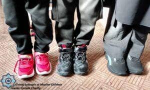 Close-up of children's feet wearing new shoes, signifying clothing provisions funded by crypto donations. Islamic relief for Muslim children aided by USDC.