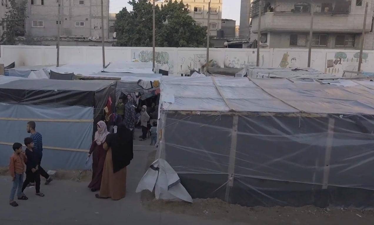 People amidst temporary shelters in a community, receiving support for skills training and livelihoods, facilitated by crypto donations like Bitcoin.