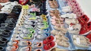 Rows of children's shoes for donation, including sneakers and ballet flats, a tangible representation of crypto Khums being channeled to aid needy children.