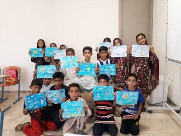 Children proudly display their artwork of marine life in a classroom, demonstrating the impact of educational programs supported by crypto donations, including ETH.