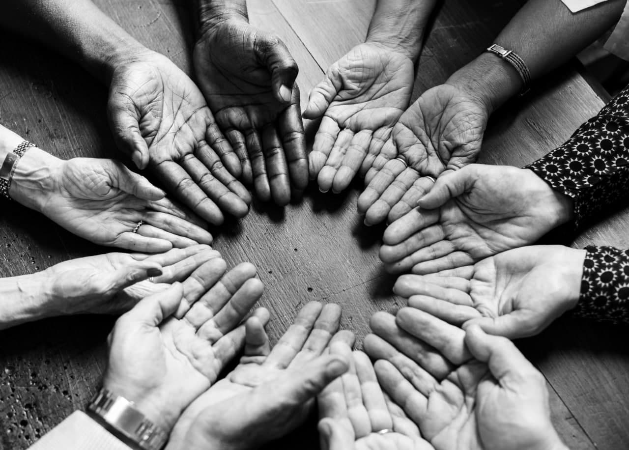 A diverse group of people with open hands forming a circle, ready to receive or give support. This image symbolizes community building and access to resources, supporting social justice initiatives with crypto donations like BTC.