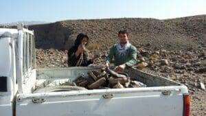 Two people loading stones into the back of a pickup truck in a rocky, arid landscape, hinting at manual labor for relief efforts supported by ETH crypto donations.