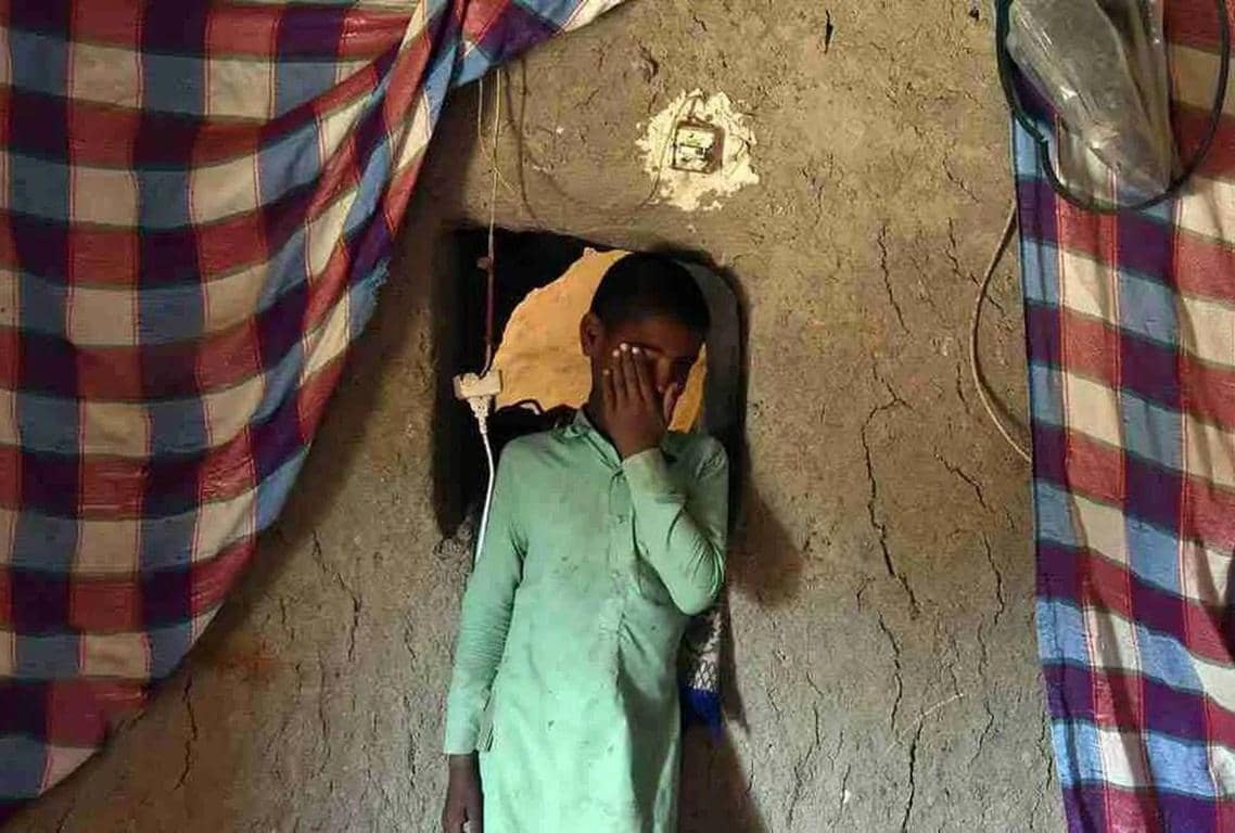 Young boy covering his eyes in a humble dwelling, symbolizing the need for Zakat al-Fitr donations via TRON to support the poor and purify fasts during Ramadan.