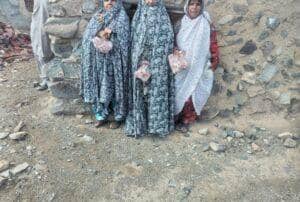 Three women receive meat donations, symbolizing the distribution of Qurbani through modern cryptocurrency like USDT, aiding needy Muslim communities in charitable endeavors.