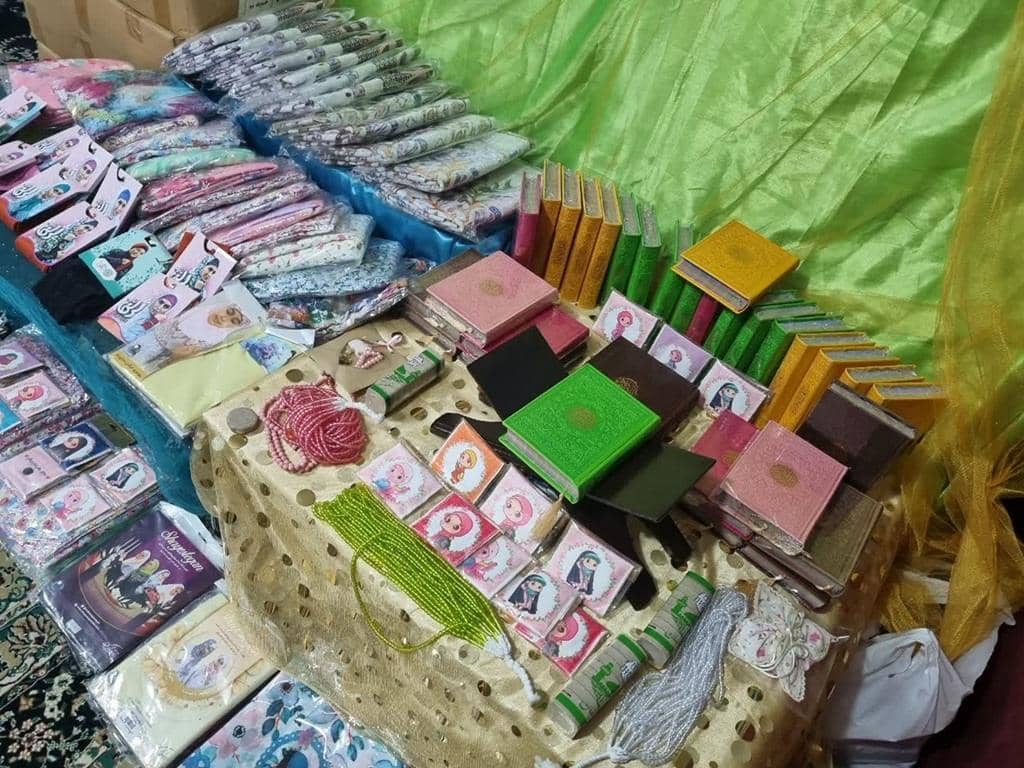 Small ornate books and prayer beads arranged for Zakat al-Fitr distribution, supporting Muslim community aid with SOL.