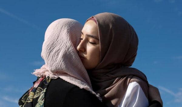Two Muslim women embracing, symbolizing the importance of humanity in Islam, compassion, and kindness; donation facilitated by BTC.