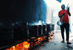 Man stirring large pots over open flames, preparing food for relief efforts in Palestine. Crypto donations like Tether support this vital aid.