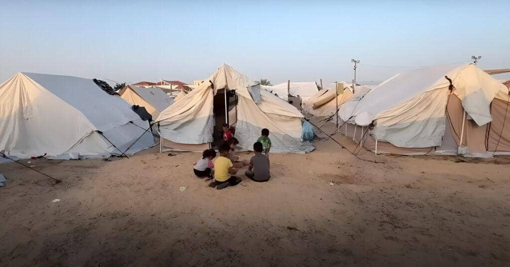 Children in a refugee camp with tents in the background, symbolizing the urgent need for aid. Your crypto donation, processed via Solana, provides food, water, and medical relief to displaced families in Rafah.