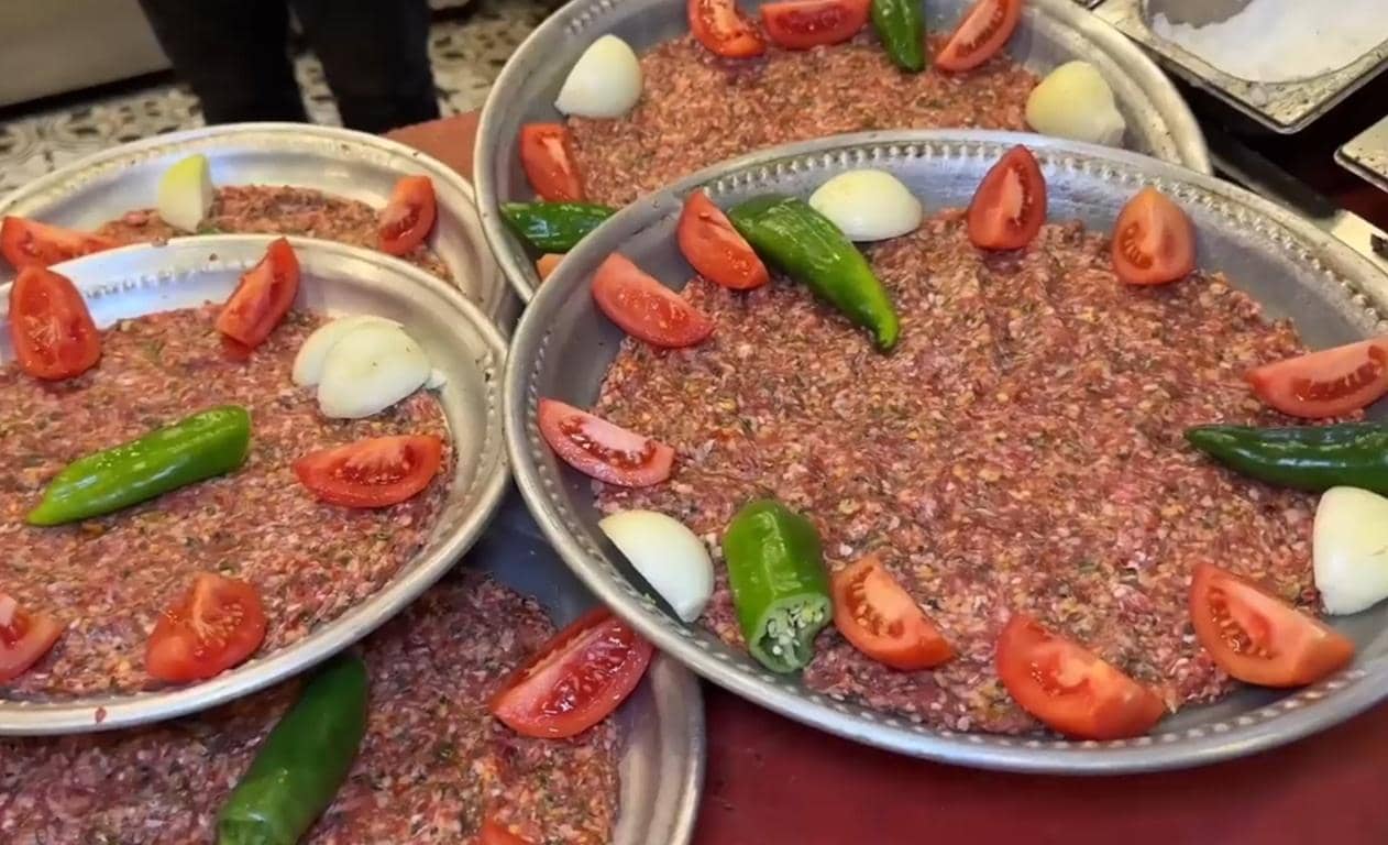 Platters of raw ground meat prepared for Aqiqah Qurbani, topped with tomatoes, onions, and green peppers. Support this act of gratitude with Bitcoin.