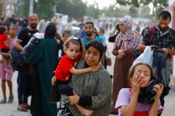 A group of displaced refugees on the Lebanon-Syria border, including women and children, walking with belongings. Showing support via crypto donations, like BTC, helps provide emergency shelter, food, and medical care.