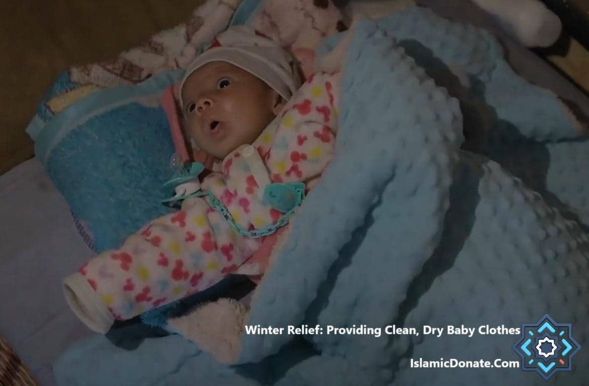 Winter relief for vulnerable families, showing a baby wrapped in blankets, crypto-funded aid provides warm clothes and shelter. Donation via ETH.