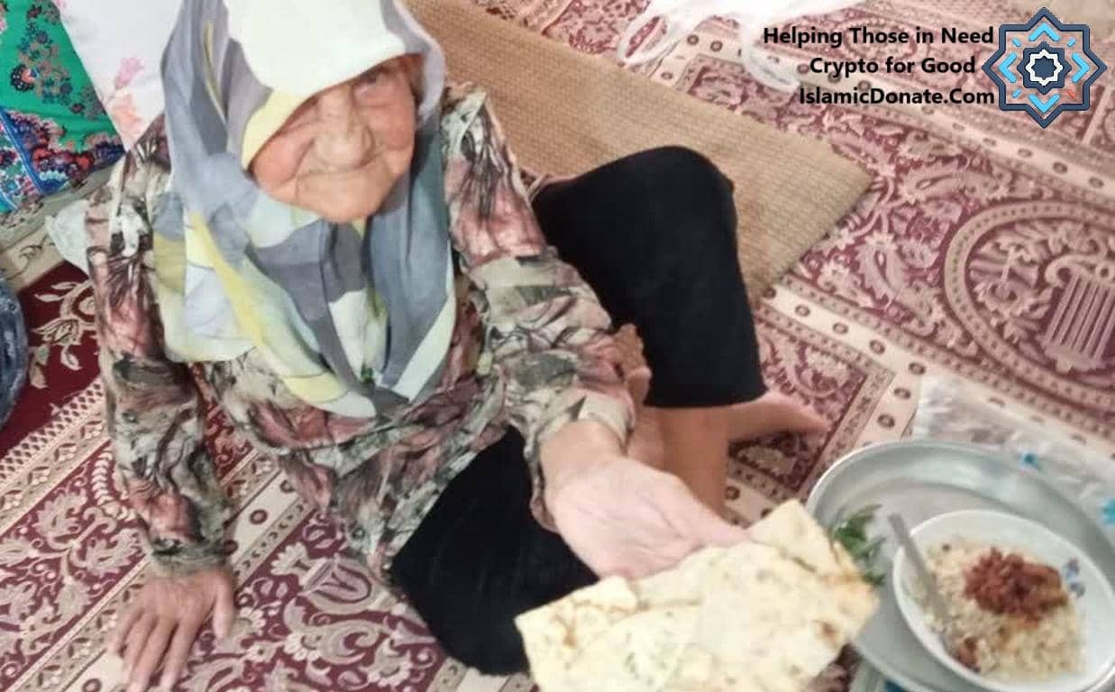 Elderly woman in hijab receiving a meal of rice and flatbread, enabled by crypto donations like BTC.