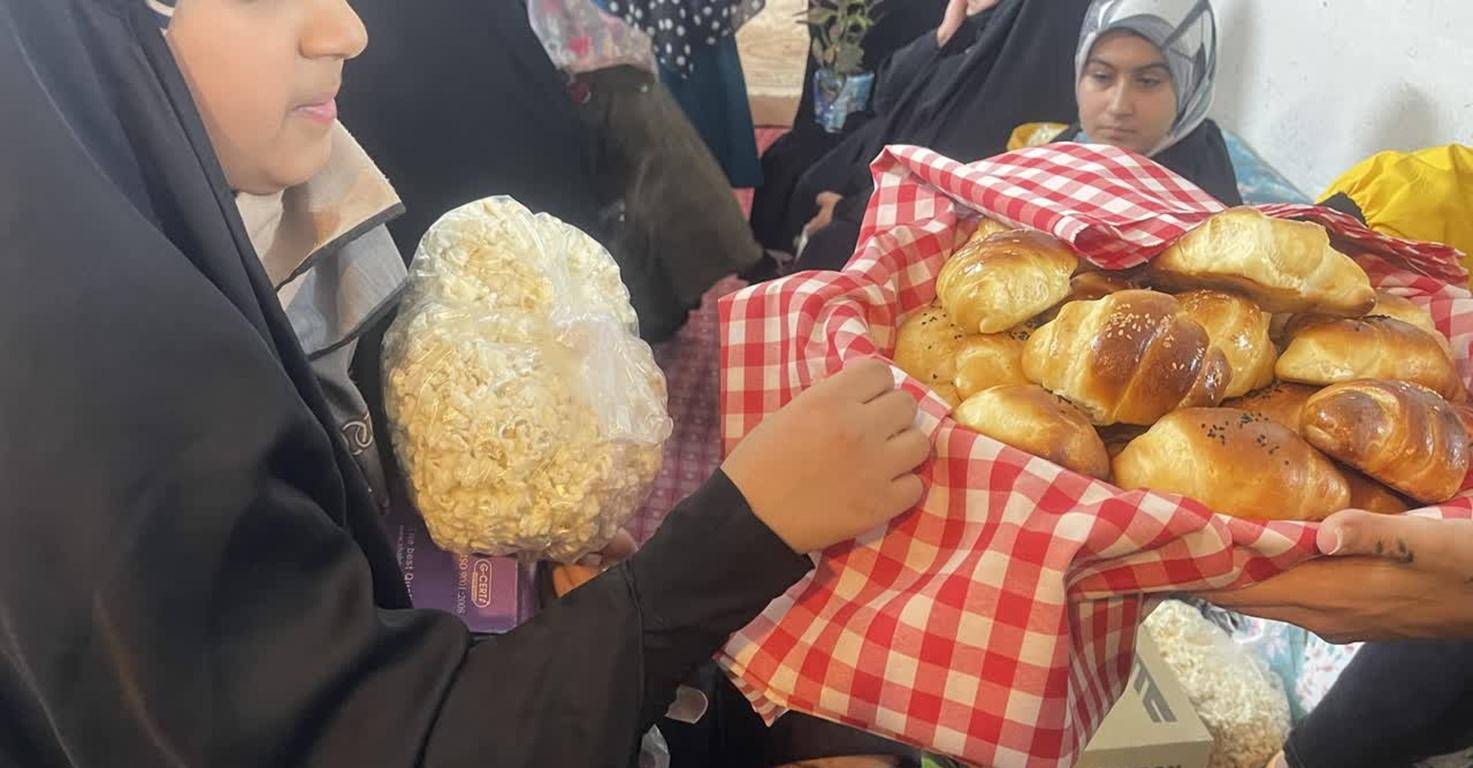 A child in hijab holds a bag of popcorn. Another person presents a basket of freshly baked bread adorned with sesame and black seeds, all part of crypto zakat donations to aid fasting families.