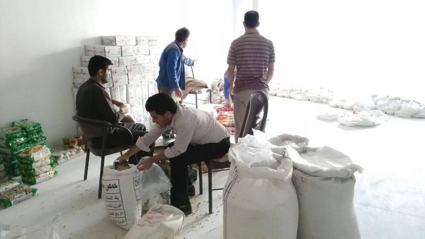 Volunteers preparing food packages for distribution, with stacks of boxed goods and large sacks of flour, symbolizing crypto zakat donations.