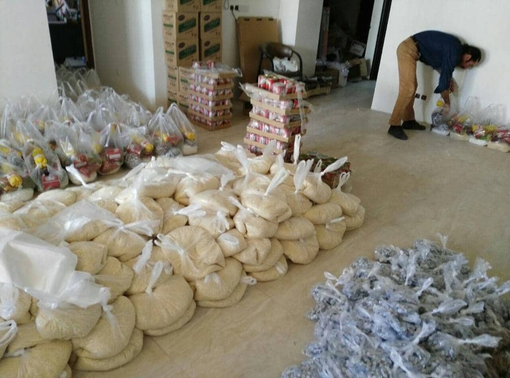 Volunteers organizing food packages for donation, including rice and other staples, supported by crypto like ETH for global relief efforts.