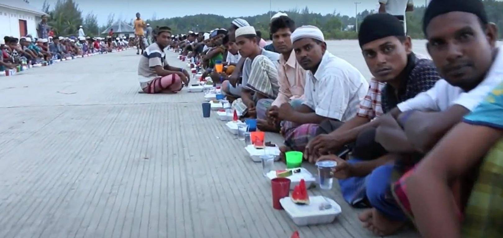 Fasting Muslims sit in rows for Iftar meals, with food packages and cups laid out, supported by crypto donations like ETH.