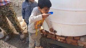 Child drinks water from a tap on a large white tank, symbolizing crypto-supported aid bringing clean water to needy families. Includes key phrases: direct donation, secure, private, fast, transparent.