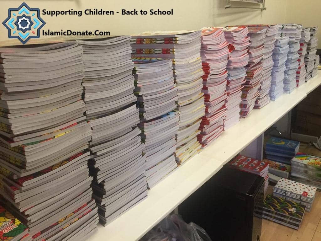 Stacks of educational books and notebooks for children, part of a back-to-school program supported by USDT donations, enabling literacy and digital skills for underprivileged youth.
