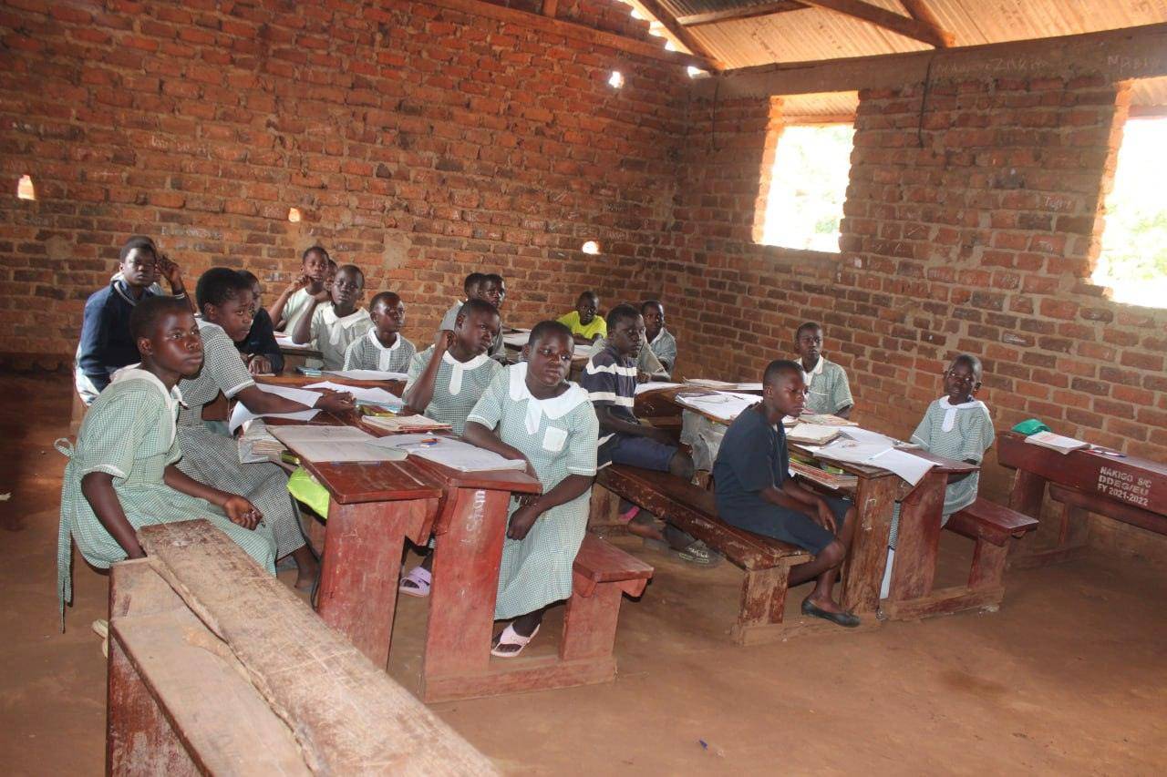 Children in a brick classroom, learning in rustic conditions, supported by crypto donations in BTC for educational empowerment and literacy programs.
