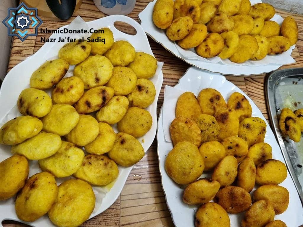 Plates piled high with freshly fried Meethi Tikiyan, a traditional sweet snack prepared for Nazr Imam Ja'far al-Sadiq on 22 Rajab. These are distributed as charitable food donations.