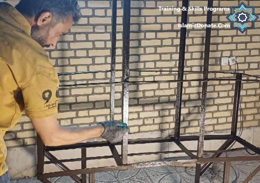 Man painting a metal structure, representing training and skills programs for sustainable livelihoods funded by crypto Sadaqah. Keywords: Sustainable Livelihoods, Skills Programs, Crypto Sadaqah, Islamic Charity, Donation.