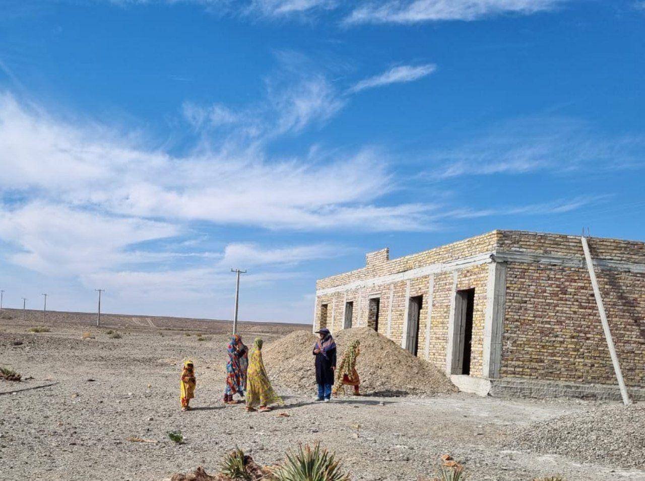 Group of women and a child standing near a partially constructed building in a dry, dusty area; implies support for social justice and poverty alleviation through cryptocurrency donations, contributing to empowerment and community building, with a donation facilitated by RLUSD.