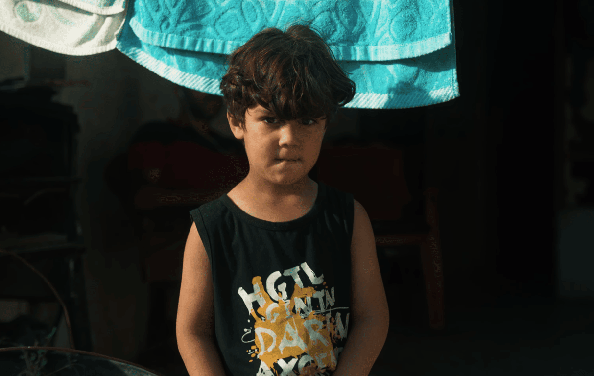 Child looking at camera, symbolizing the recipients of Khums donations made via cryptocurrency like ETH, supporting orphans and needy families.