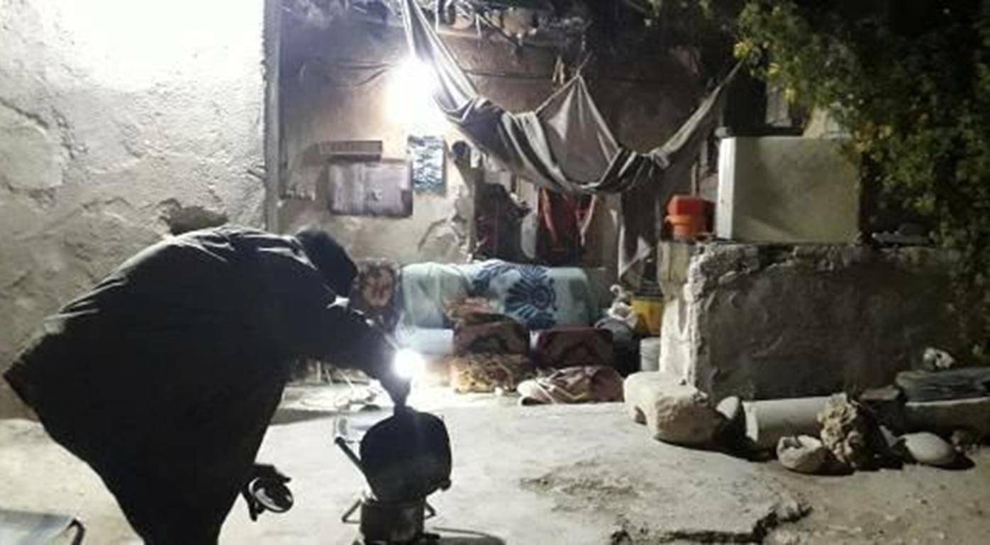 Person using a lantern in a dimly lit, modest dwelling, symbolizing the transformative power of crypto Sadaqah to provide hot meals, relief, and sustainable livelihoods for the needy, with ETH donations bringing hope.
