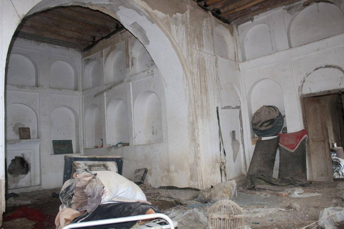 Ramshackle building interior with arched niches, showing signs of disrepair. Supplies are piled up, suggesting aid distribution, possibly from crypto donations via Solana.