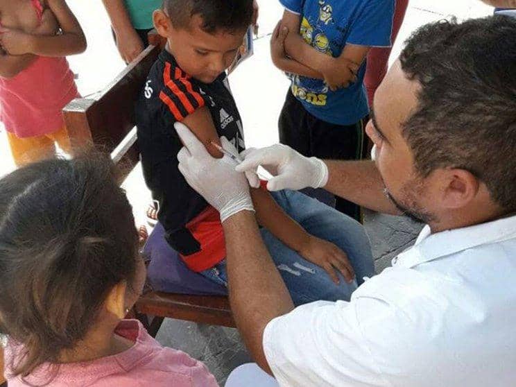 A healthcare worker administers a vaccine to a child, supporting the health of vulnerable populations. This vital aid is processed via stablecoin. This supports children's healthcare needs.