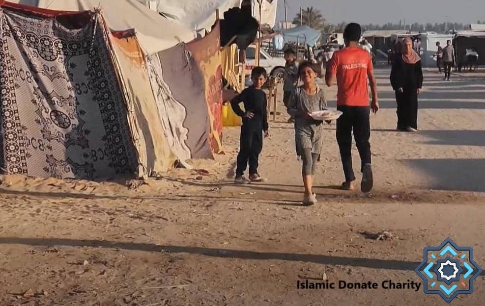 Children receiving food aid in a camp setting, a boy in a red shirt with PALESTINE on it walks away, support for the Muslim community via crypto donations like ETH.