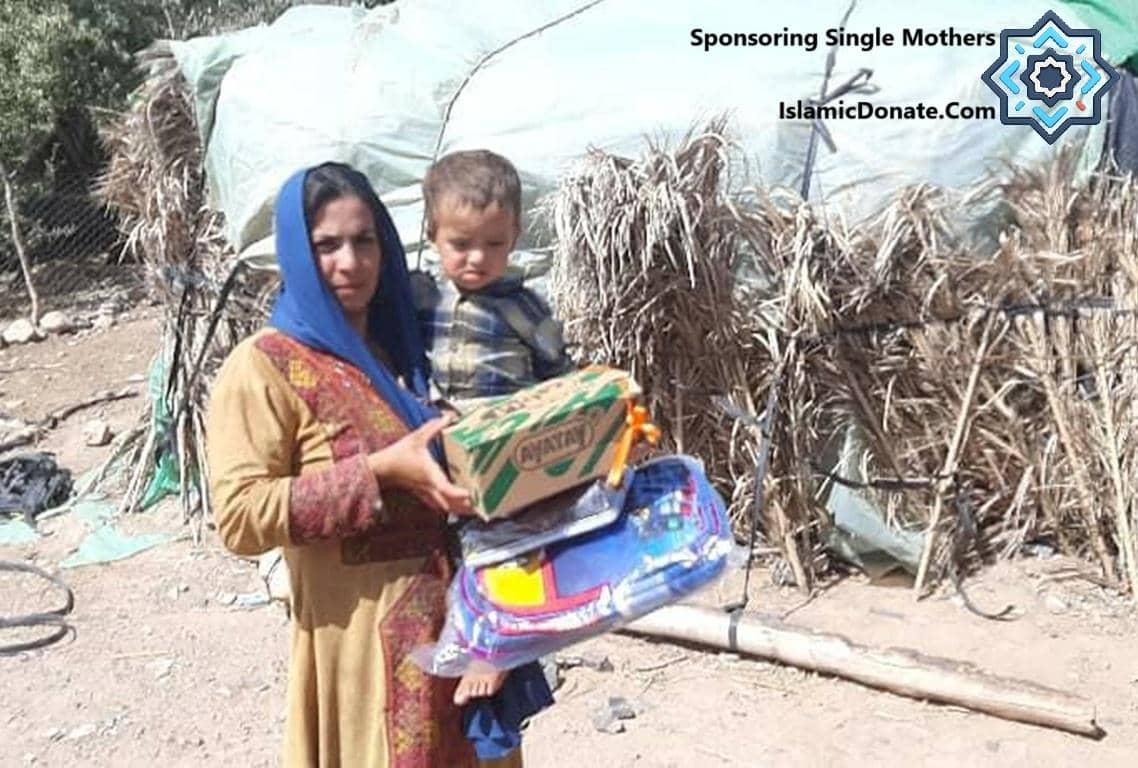 Mother and child receiving a donation in a camp. Sponsoring mothers with crypto donations like PayPal USD for Laylatul Qadr ensures aid reaches those in need.