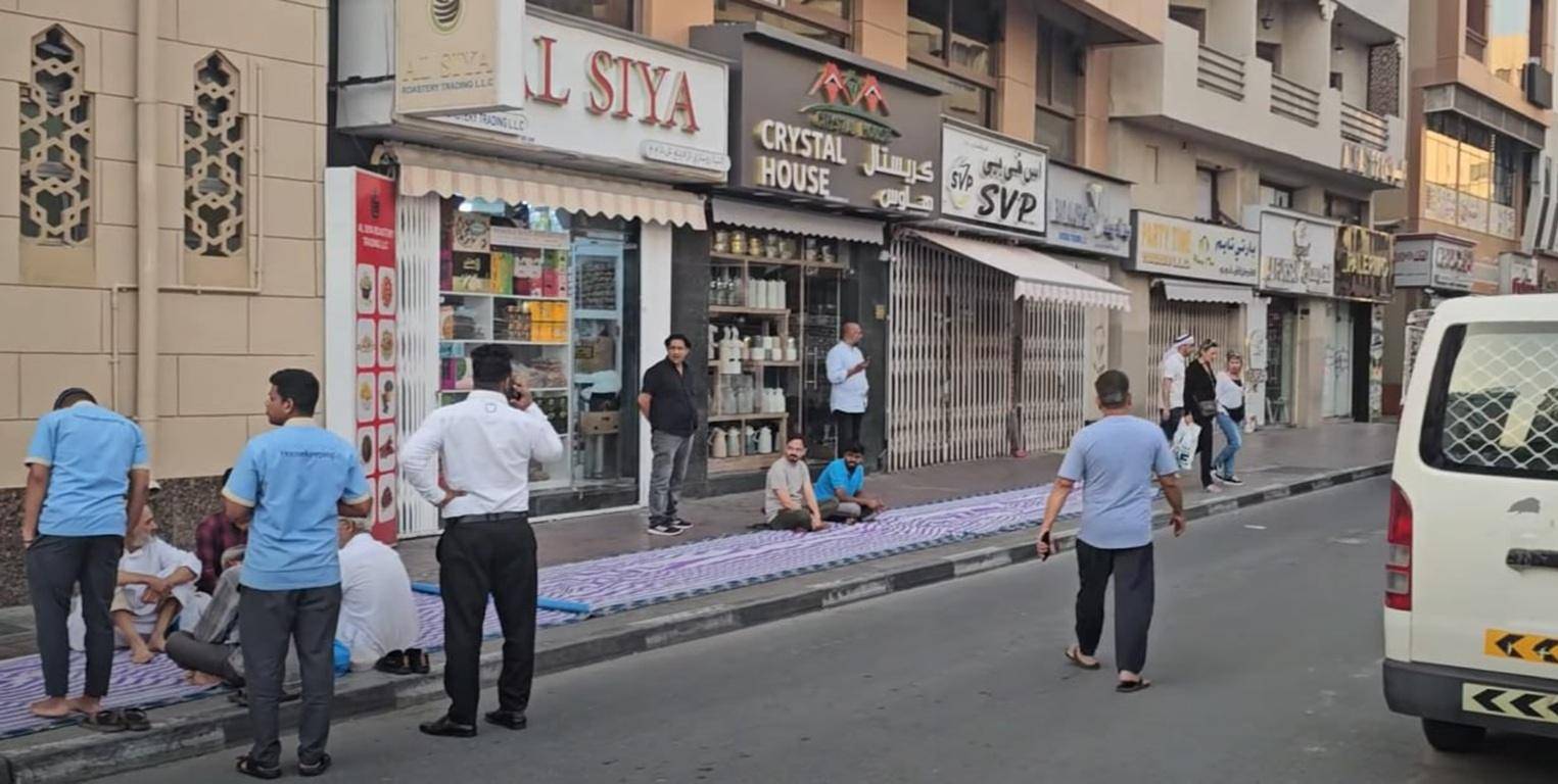 People gathered on mats on a street to receive Ramadan iftar, supporting Qurbani animal sacrifice and aid for the needy.
