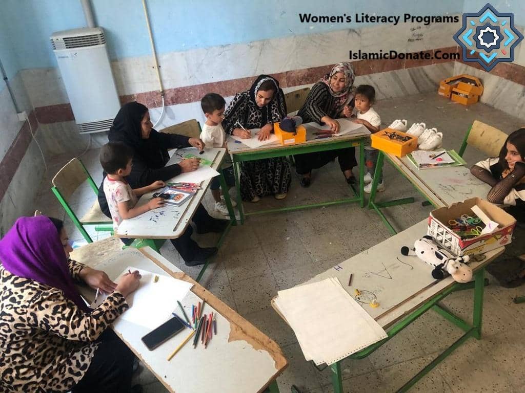 Women's Literacy Programs class in session, possibly funded by BTC donations, showing children and adults learning and creating art. IslamicDonate.Com logo visible.