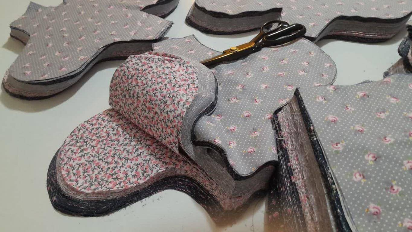 Stacks of fabric cut into sanitary pad shapes, ready for sewing. Supported by crypto donations like ETH.