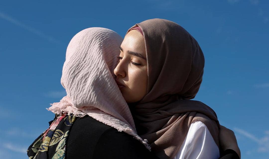 Two Muslim women embracing, symbolizing the importance of humanity in Islam, compassion, and kindness; donation facilitated by BTC.