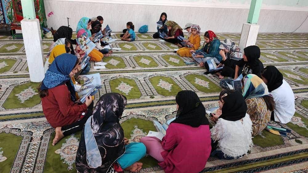Children sitting on a carpeted floor, reading books. Donation for education is facilitated by crypto, with ongoing rewards achieved through Halal Crypto Giving via platforms like RLUSD.