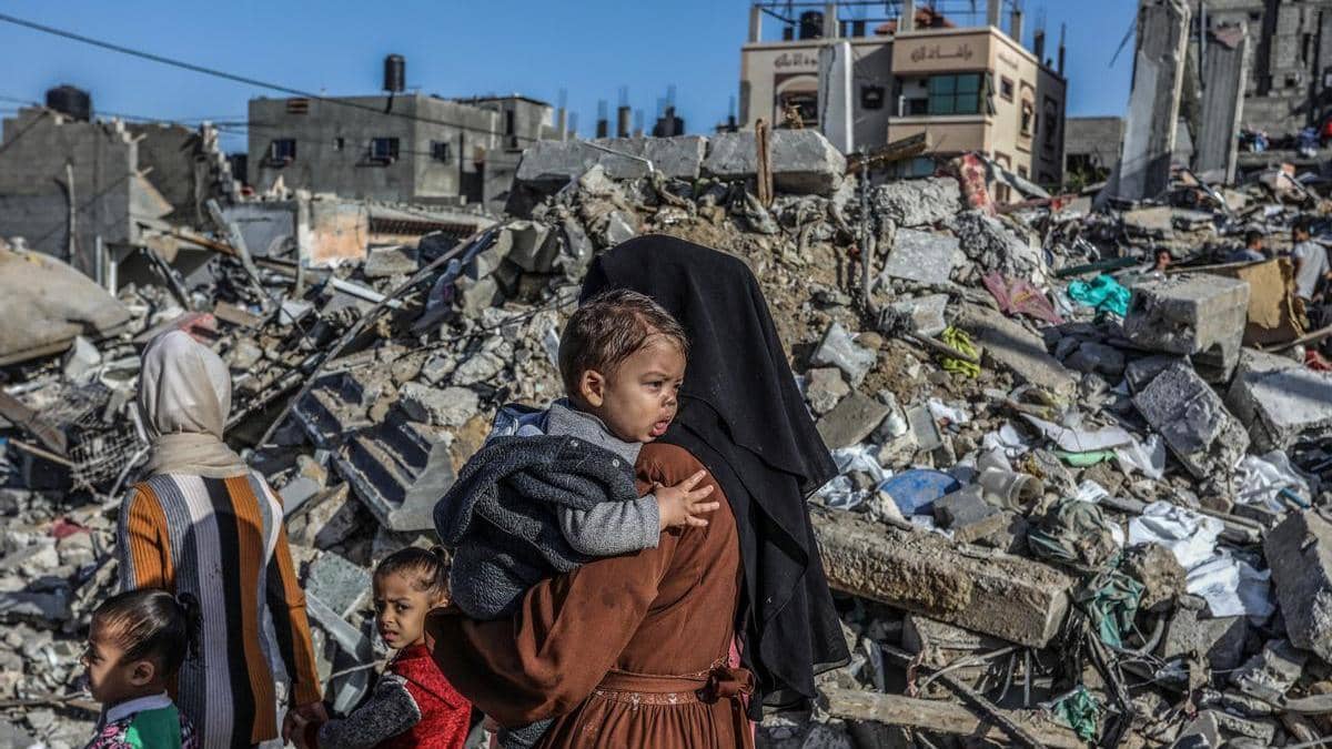 A woman carries a child through rubble in Rafah, Gaza, highlighting the urgent need for cryptocurrency donations for essential aid and humanitarian relief.