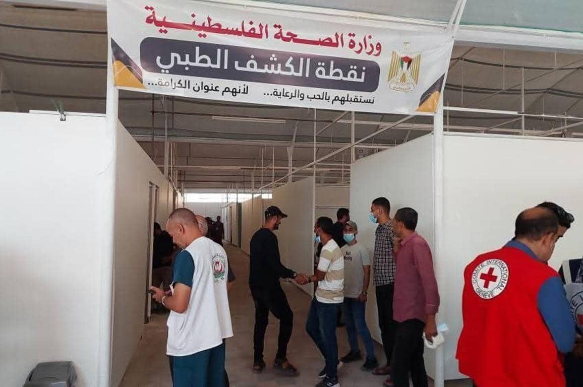 Palestinian Ministry of Health medical screening point sign. People gather inside a temporary clinic structure, with some wearing Red Cross vests, indicating humanitarian aid. Donate Crypto for Palestine provides food, shelter, and medical aid with ETH.