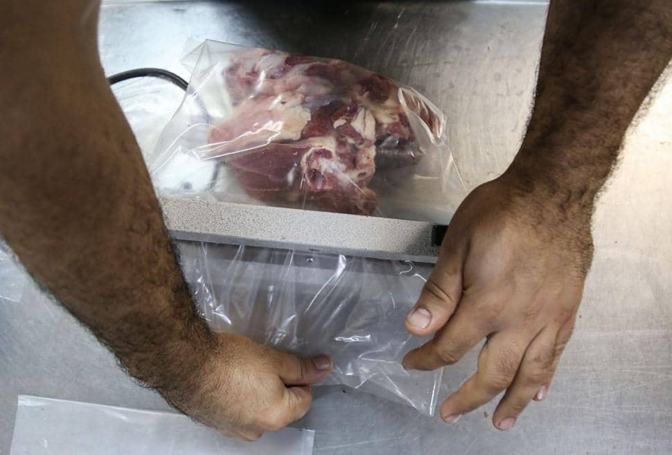 Hands sealing a plastic bag of sacrificial meat for distribution during Eid al-Adha, supported by XRP donations.