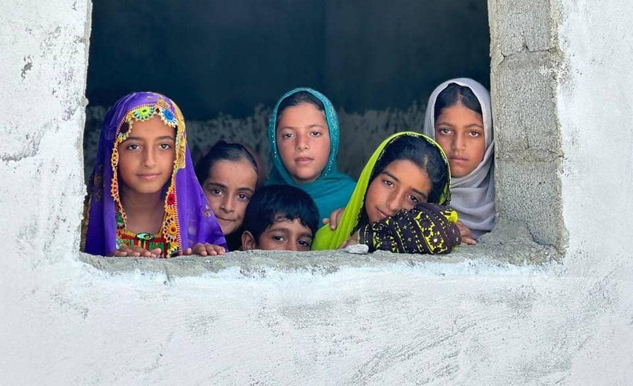 Children looking out a window, representing fulfillment of Kaffarah obligations through crypto donation, with aid reaching needy communities funded by LTC.