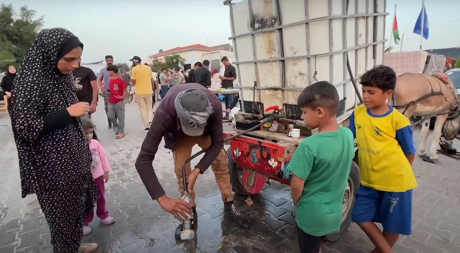 People receiving aid including water distribution in Palestine, donation via Arab Emirates Dirham processing.