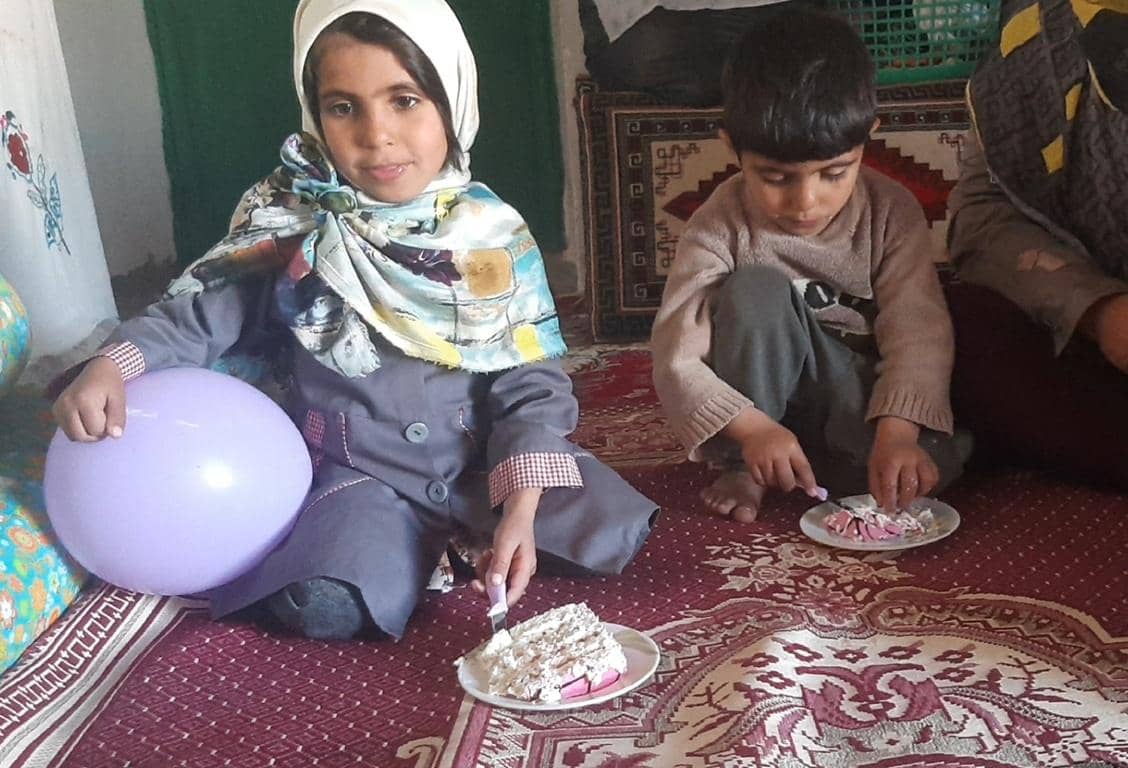 Children celebrating Prophet's birthday with cake and a balloon, with donations made possible via BTC.