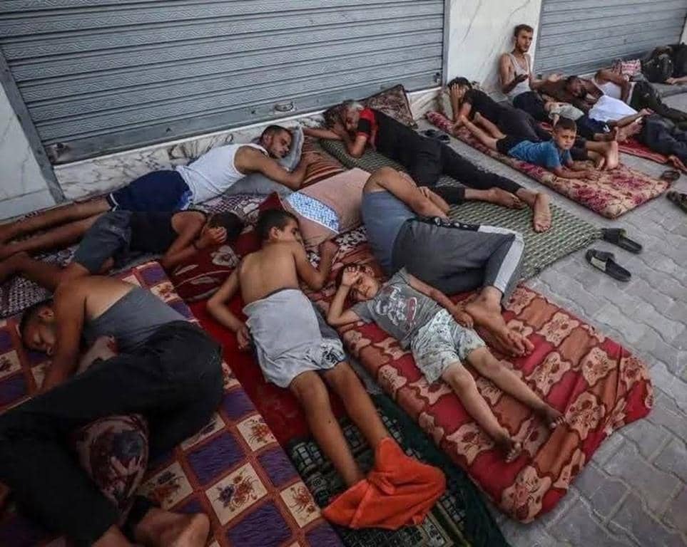 People sleeping on mats outside a building, enduring hardship. Humanitarian aid delivered via 100% donation crypto such as BTC provides essential relief to vulnerable populations in Gaza, offering hope amidst crisis.