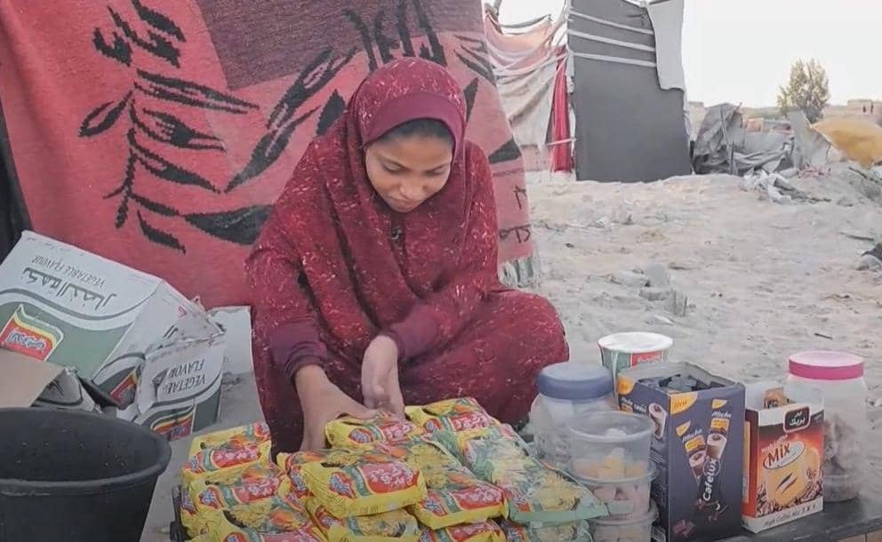 A young girl in a headscarf and maroon dress sorts food items, an act of aid for working children, with donations possibly supported by ETH.