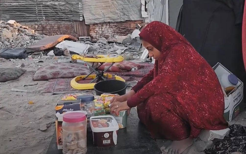 A child in a red headscarf sorts through donated food items, including dried goods and packaged snacks, in a makeshift shelter. This image highlights the plight of working children and the need for aid, supported by ETH donations.