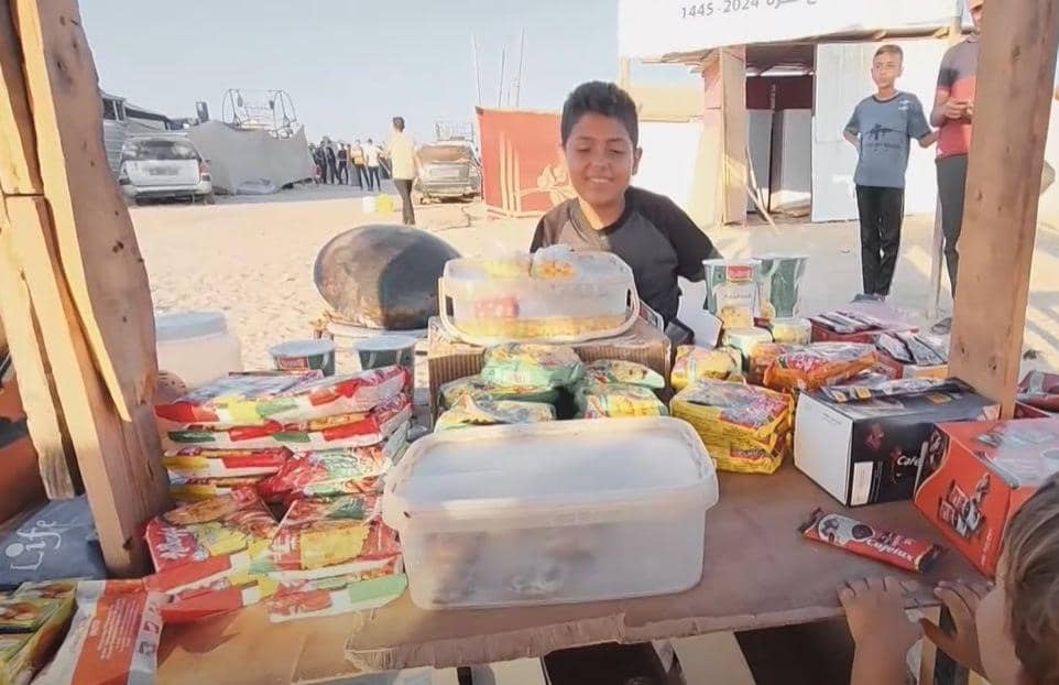A smiling boy works at a stall selling food and snacks, Universal Children's Day focus on working children, with donations supported by BTC.