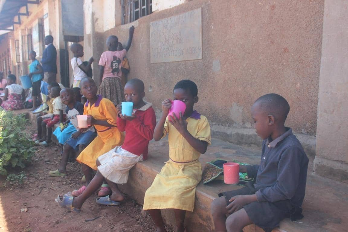 Children drinking from colorful cups, representing access to clean water in Uganda, supported by Solana crypto donations for crucial aid and water well projects.