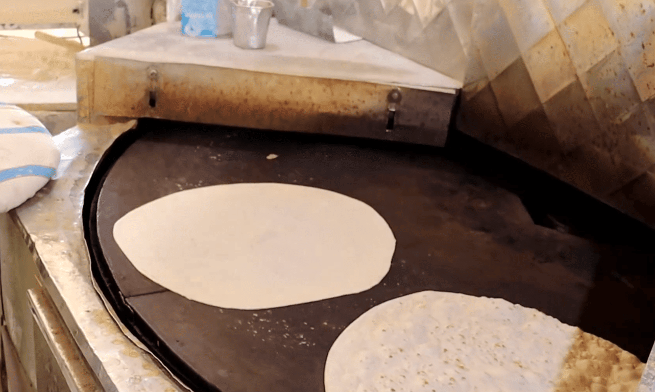 Two flatbreads being cooked on a hot griddle, representing sustenance provided through anonymous crypto donations via Bitcoin. These donations offer vital aid and help feed hungry families.
